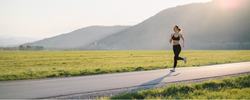 Runner moving along a mountain road to introduce the article's theme of running becoming easier over time